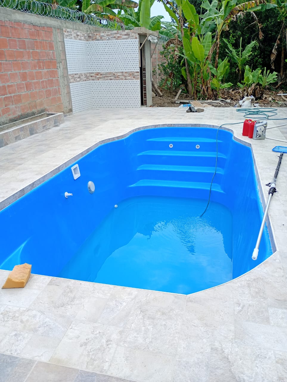Piscina en fibra instalada en patio con acabado en cerámica